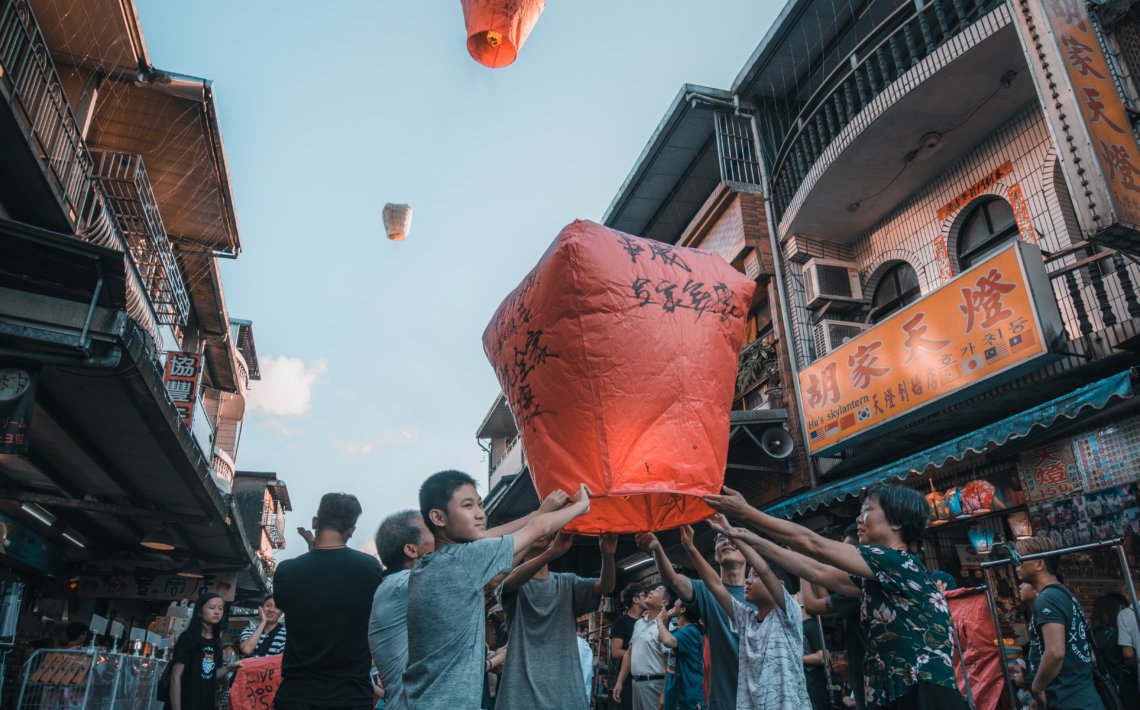 unknown persons holding red paper lantern outdoors