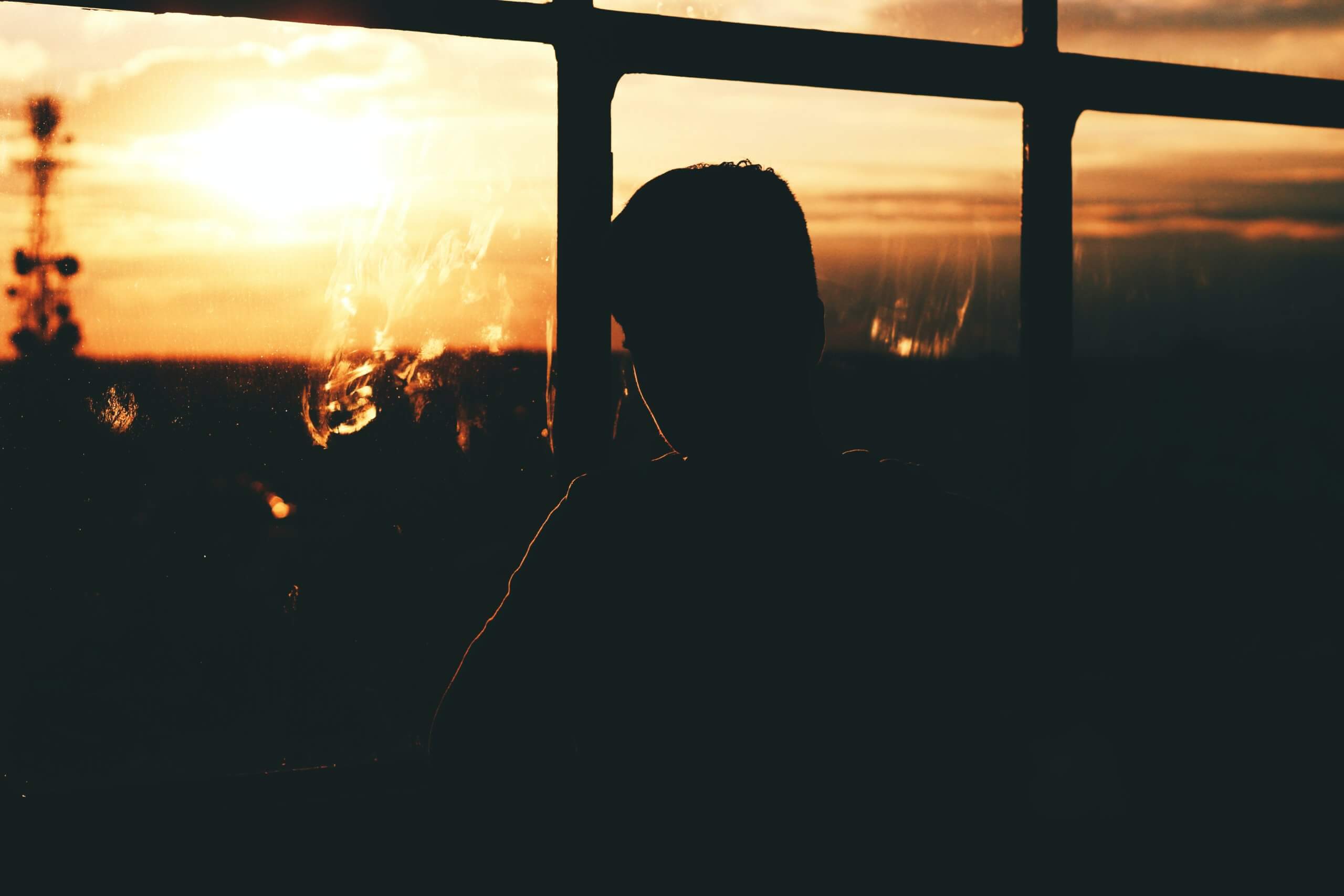 silhouette of a person by a glass window during sunset
