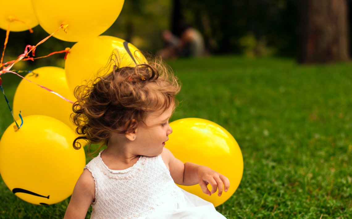 girl sitting on grass near balloon
