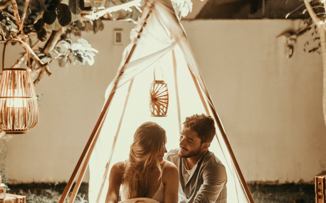 couple sitting inside tepee hut with lights
