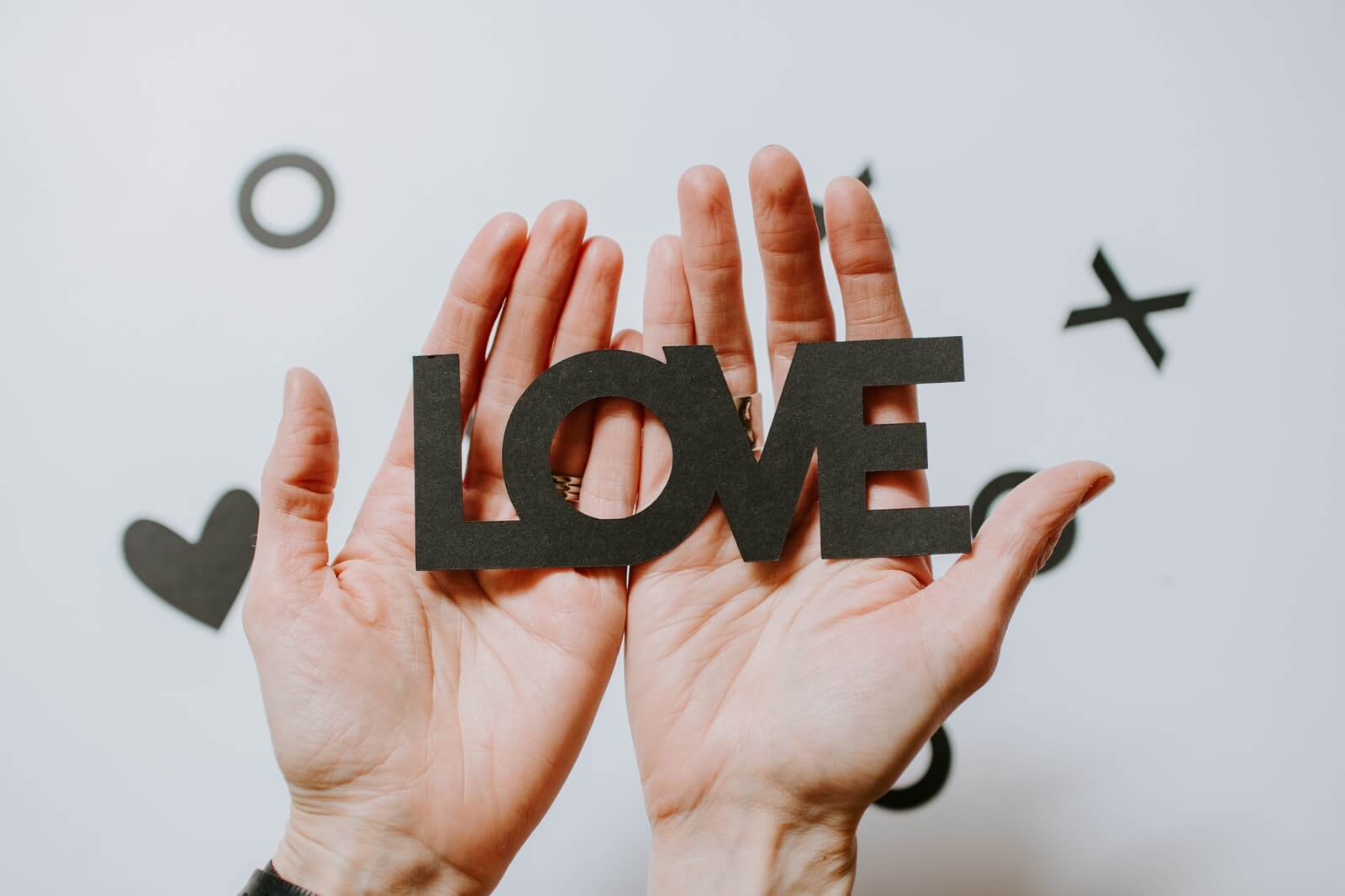 person holding love word cutout paper