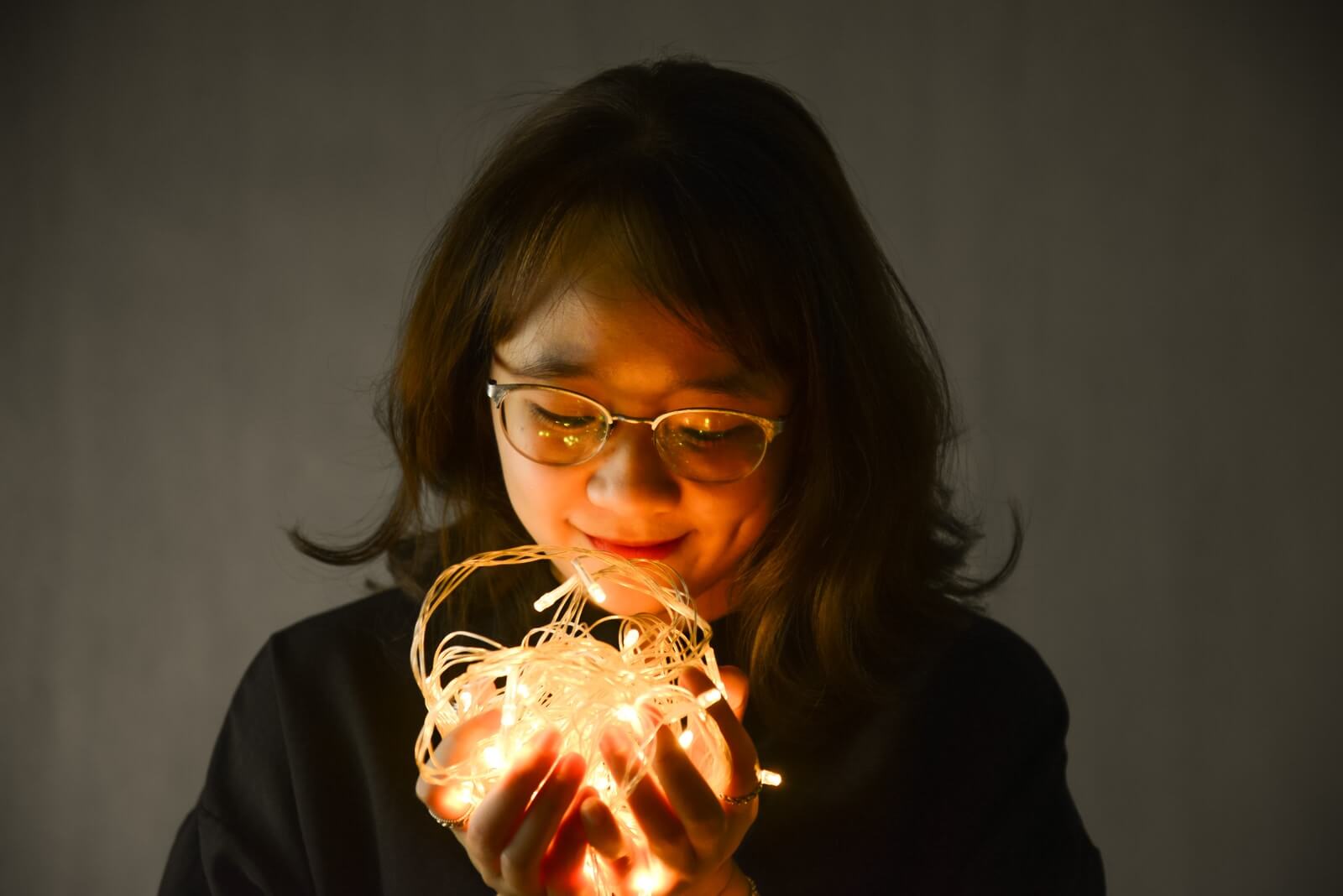 woman in black framed eyeglasses holding lighted candle